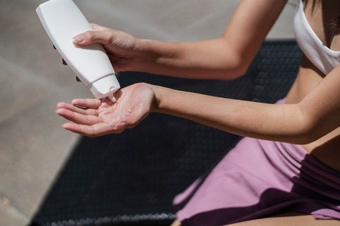 Close-up of a woman applying sunscreen outdoors, highlighting skincare and wellness