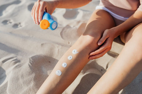 Close-up of applying sunscreen on legs at the beach for skin protection